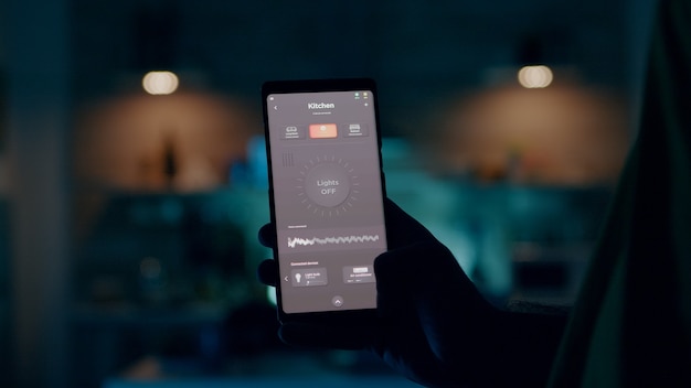 Photo gratuite personne contrôlant la lumière de la maison à l'aide de l'écran tactile de l'application smart home pour l'allumer par mobile ...