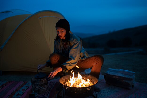 Personne cuisinant au feu de camp