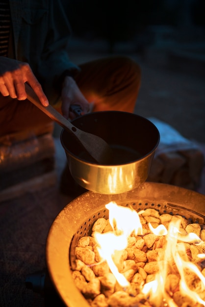 Photo gratuite personne cuisinant au feu de camp