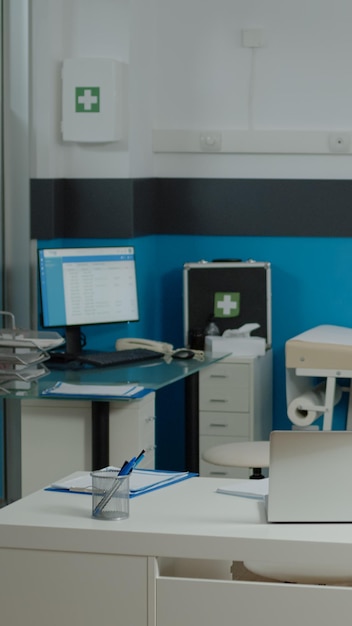 Photo gratuite personne dans le bureau du médecin avec des meubles modernes dans un établissement médical. cabinet d'examen vide pour spécialiste de la santé. gros plan du bureau blanc avec ordinateur portable, stéthoscope et stylos