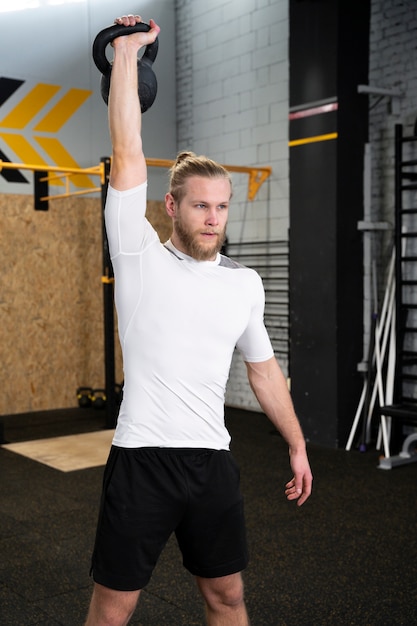 Personne dans la salle de sport à l'aide de kettlebells