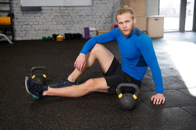 Personne dans la salle de sport à l'aide de kettlebells