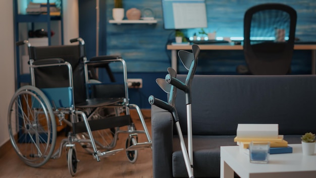 Personne dans le salon avec fauteuil roulant et béquilles pour aider au transport. Espace vide avec équipement d'aide à la marche pour aider les personnes souffrant d'un handicap chronique. Mobilité physique