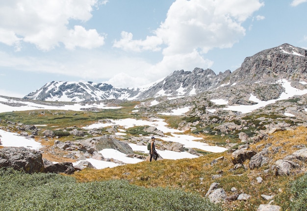 Personne debout près de la montagne sous un ciel nuageux pendant la journée