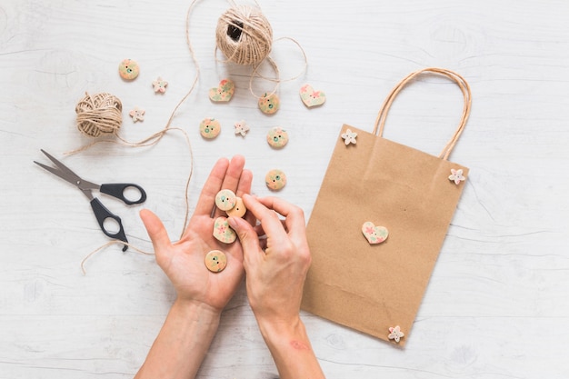 Une personne faisant un sac shopping décoré avec un bouton en bois