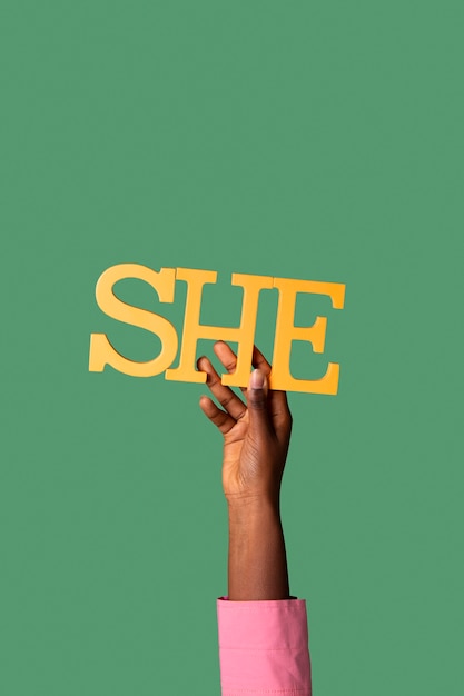 Personne fluide de genre tenant un pronom féminin sur papier