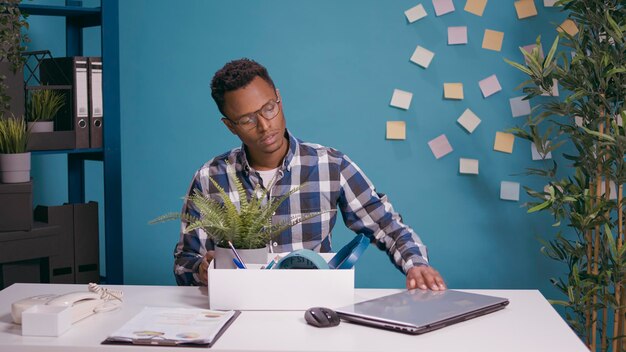 Personne frustrée emballant ses affaires dans une boîte après avoir été renvoyée de son travail de bureau. Un homme malheureux se sentant inquiet du chômage, rassemblant des choses après avoir été licencié et licencié.