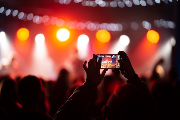 Une personne en gros plan en train d'enregistrer une vidéo avec un smartphone pendant un concert