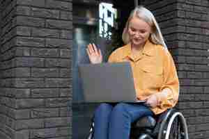 Photo gratuite personne handicapée en fauteuil roulant travaillant sur ordinateur portable