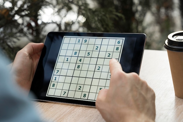 Personne jouant au sudoku sur une tablette