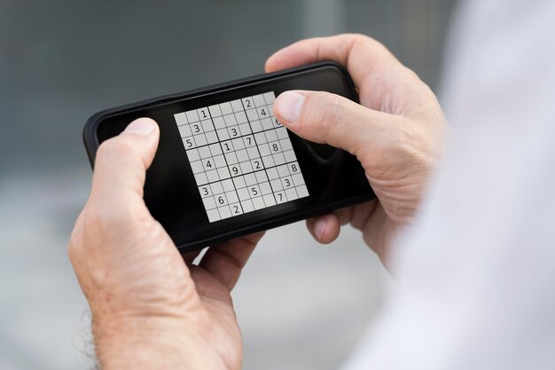 Personne jouant à un jeu de sudoku sur un smartphone