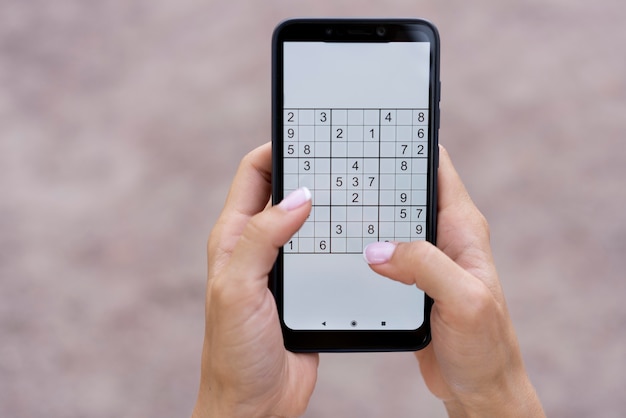 Personne jouant à un jeu de sudoku sur un smartphone