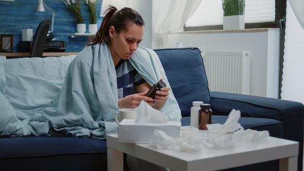 Personne lisant l'étiquette de la tablette avec des capsules et une bouteille de pilules