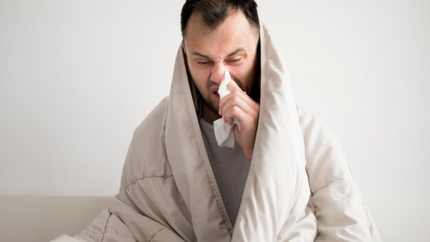 Personne malade enveloppée dans une couverture et ayant un nez qui coule