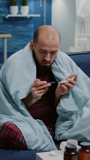 Personne malade regardant des comprimés de gélules pour soigner les symptômes de la maladie et du virus. Homme avec rhume et grippe tenant des médicaments et des pilules pour les soins de santé. Adulte malade avec des drogues