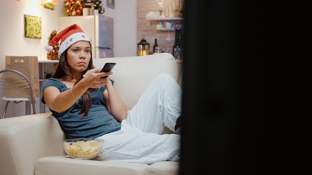 Personne malheureuse utilisant la télécommande de la télévision pour changer de chaîne