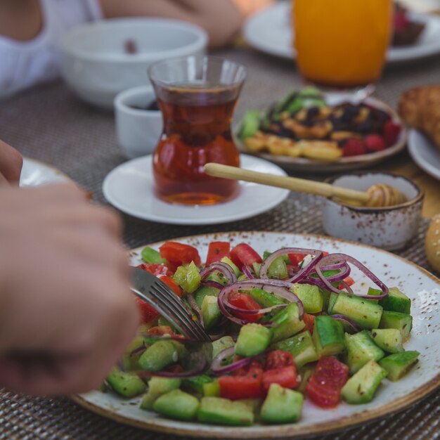 Une personne mange carré salade de tomates concombre hachées