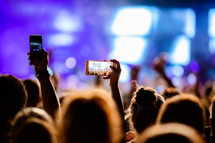 Photo gratuit personne méconnaissable photographiant avec des artistes de scène de téléphone intelligent lors d'un festival de musique