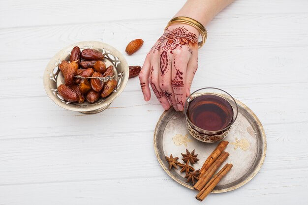 Personne avec mehndi tenant une tasse de thé sur une assiette