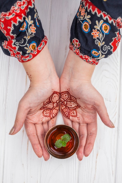 Photo gratuite personne avec mehndi tenant une tasse de thé