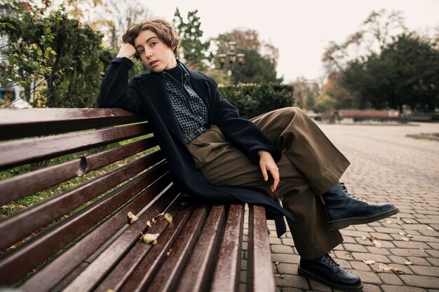 Personne non binaire assise sur un banc à l'extérieur