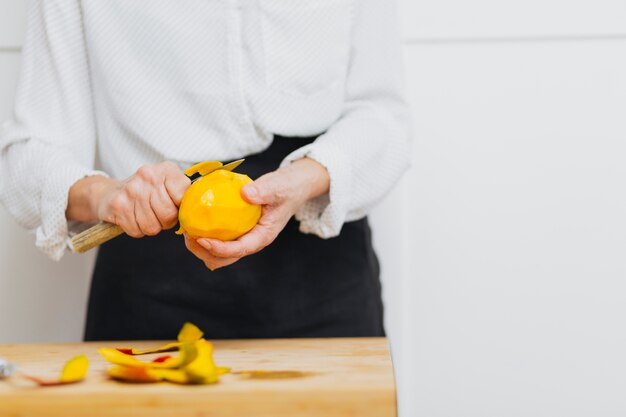 Personne non reconnaissable qui épluche des fruits