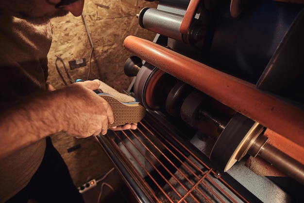 Une personne pensive expérimentée fabrique des chaussures sur mesure dans son atelier personnel.