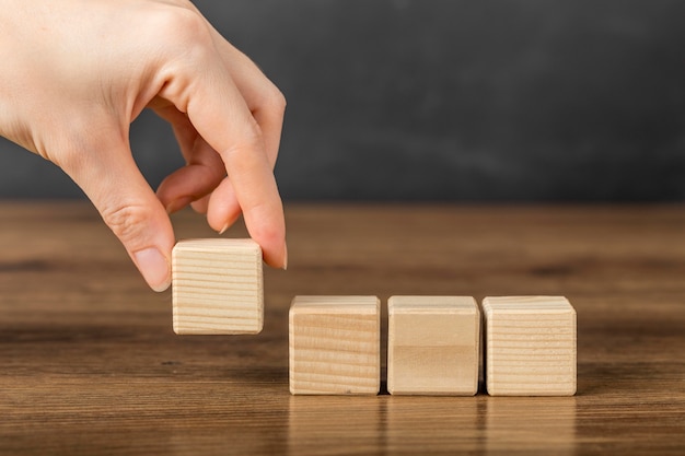 Photo gratuite personne plaçant un cube en bois à côté d'autres