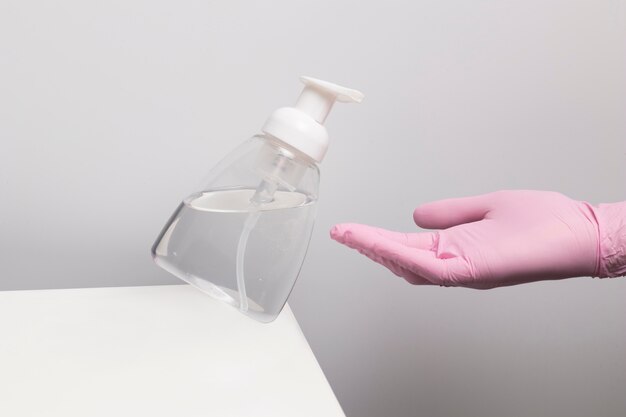Personne portant des gants et utilisant un désinfectant pour les mains