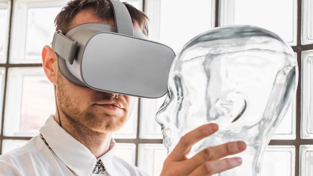 Photo gratuite personne portant des lunettes de réalité virtuelle tenant un mannequin transparent