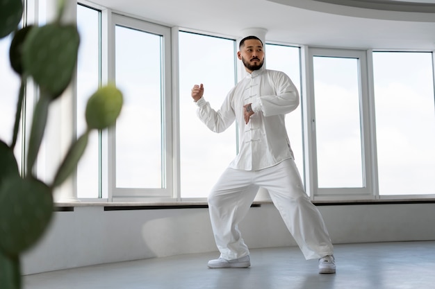 Photo gratuite personne pratiquant le tai-chi à l'intérieur