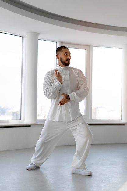 Photo gratuite personne pratiquant le tai-chi à l'intérieur