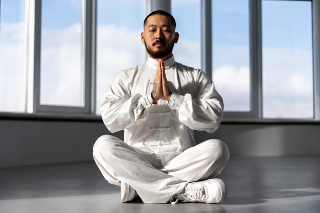 Photo gratuite personne pratiquant le tai-chi à l'intérieur