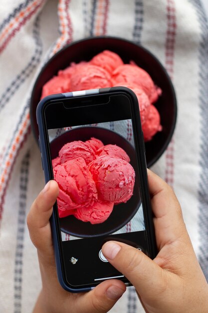 Personne prenant une photo de crème glacée sur une assiette avec un smartphone