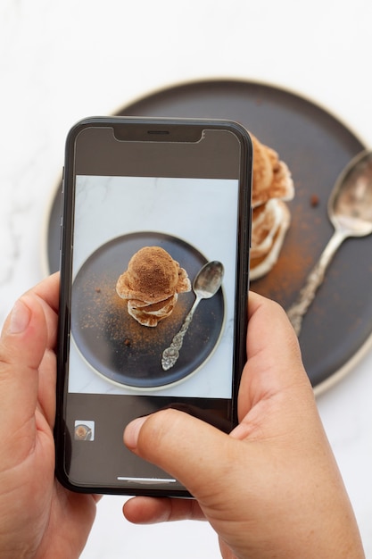 Personne prenant une photo avec un smartphone de dessert avec de la poudre de cacao