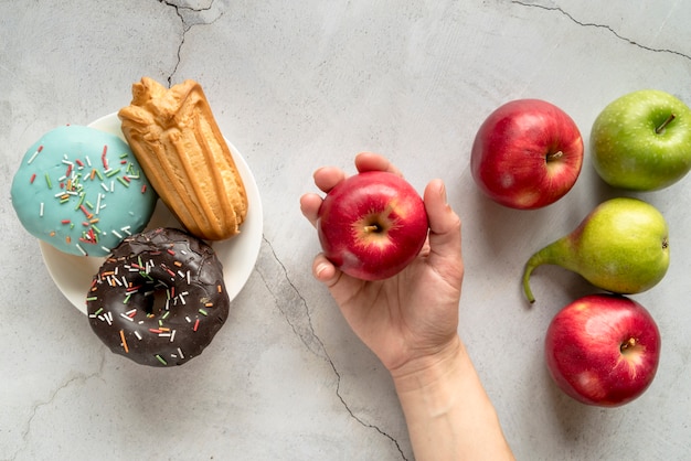 Photo gratuite personne qui choisit des fruits sur des aliments de confiserie sur fond de béton