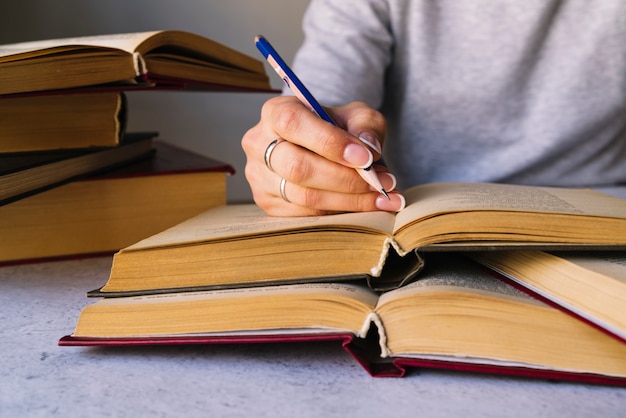 Photo gratuite personne qui écrit à côté de la pile de livres