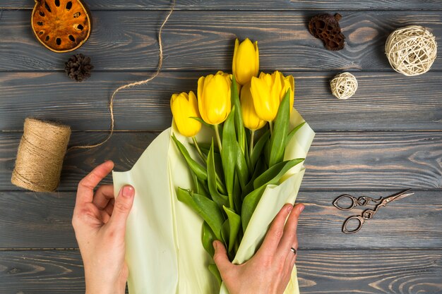 Personne qui emballe des tulipes jaunes dans du papier d&#39;emballage