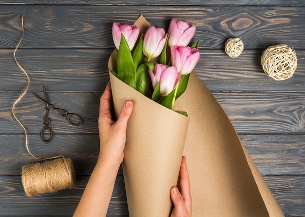 Personne qui emballe des tulipes roses dans du papier d&#39;emballage