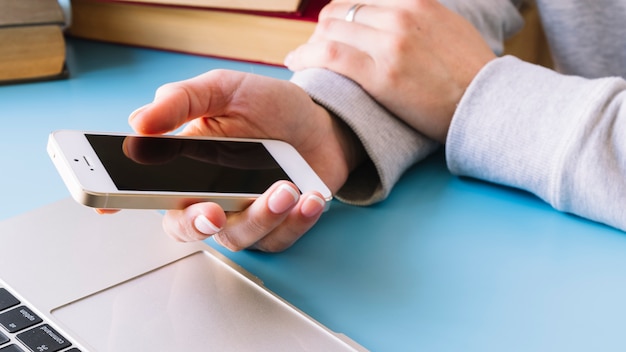 Personne qui touche un téléphone portable sur un bureau