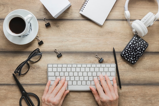 Personne sans visage en tapant sur le clavier près de la tasse de café et des écouteurs