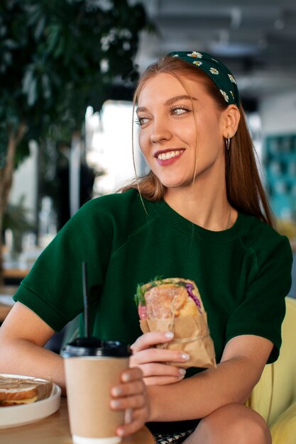 Personne tenant et dégustant des sandwichs enveloppés dans du papier