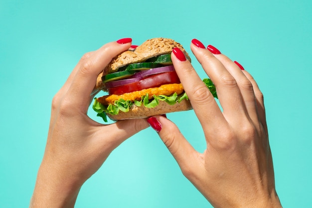 Photo gratuite personne tenant un hamburger frais et savoureux