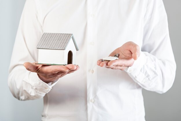 Personne tenant un jouet de maison et des clés