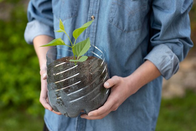 Personne tenant une plante dans un pot en plastique