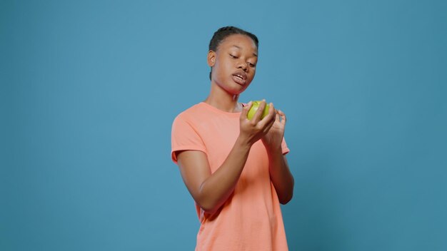 Personne tenant une pomme verte et expliquant la nutrition végétarienne, faisant la publicité d'une alimentation crue et saine. Femme aux fruits biologiques et naturels parlant de vitalité et de collation avec des vitamines