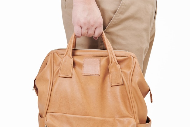 Personne tenant un sac à dos en cuir marron