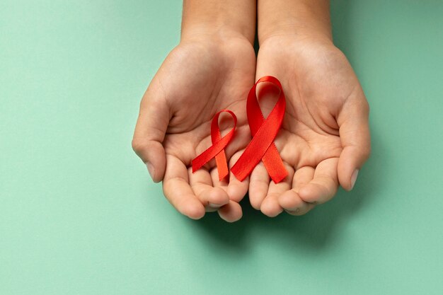 Personne tenant un symbole rouge de la journée mondiale du sida