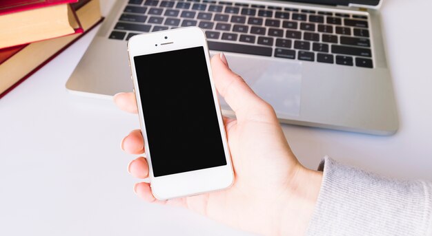 Personne tenant un téléphone portable sur un bureau