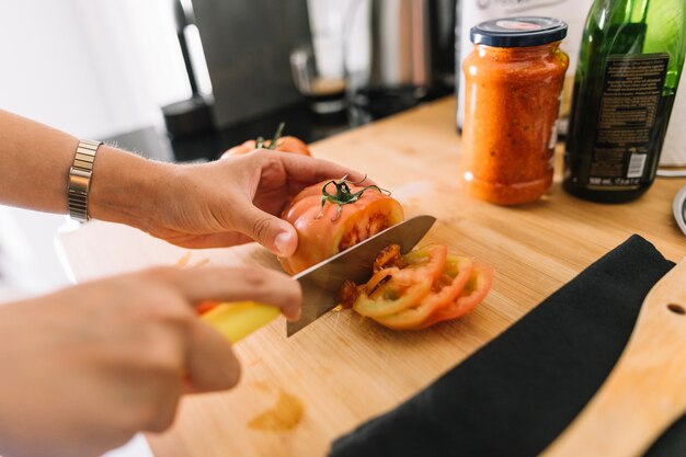 Une personne tenant des tranches de tomate sur une planche à découper